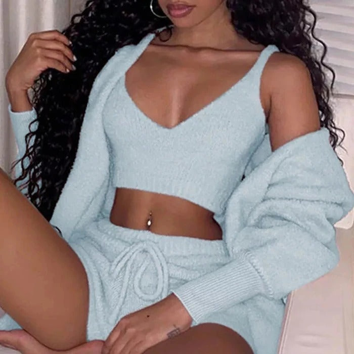 Woman wearing a light blue knit outfit sitting on a couch.