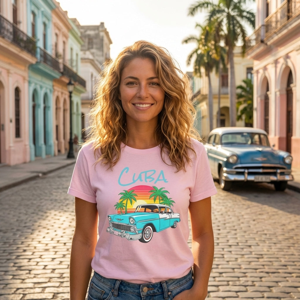 Woman wearing a pink t-shirt with a Cuba graphic design, standing on a street with vintage cars and colorful buildings.