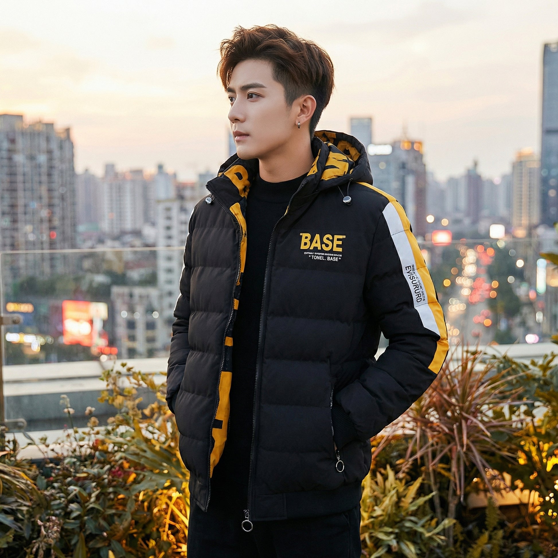 Person wearing a black and yellow puffer jacket with 'BASE' branding against an urban skyline.