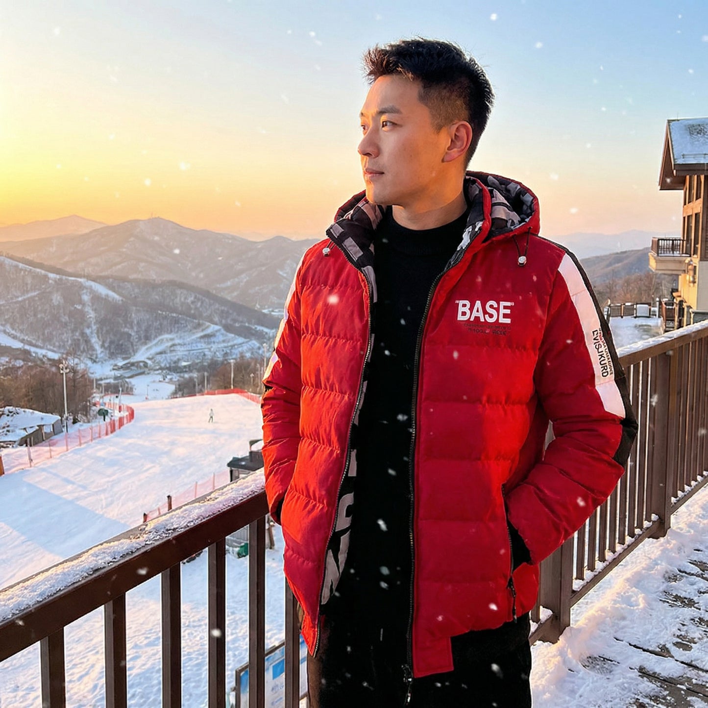 Person wearing a red puffer jacket with 'BASE' branding in a snowy mountain setting.