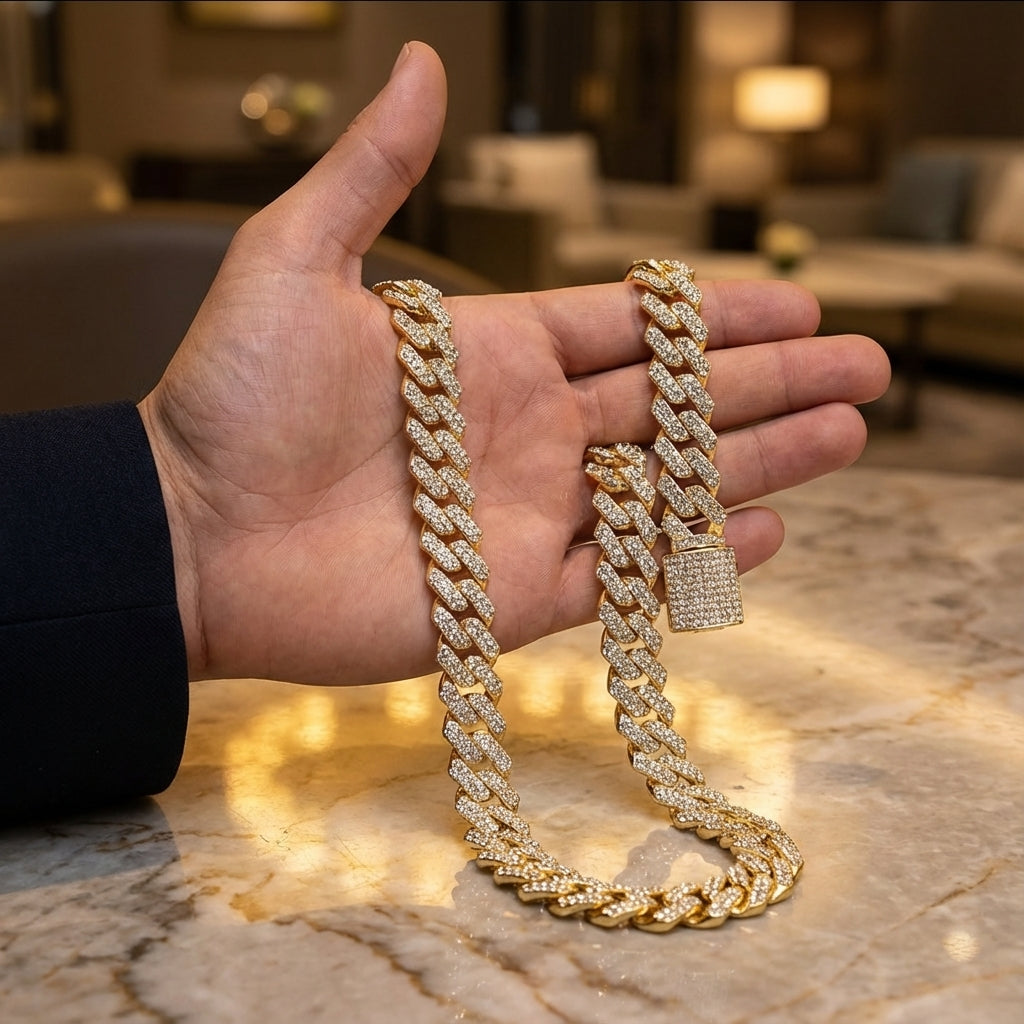 Gold chain necklace held by a hand on a marble surface with blurred indoor background