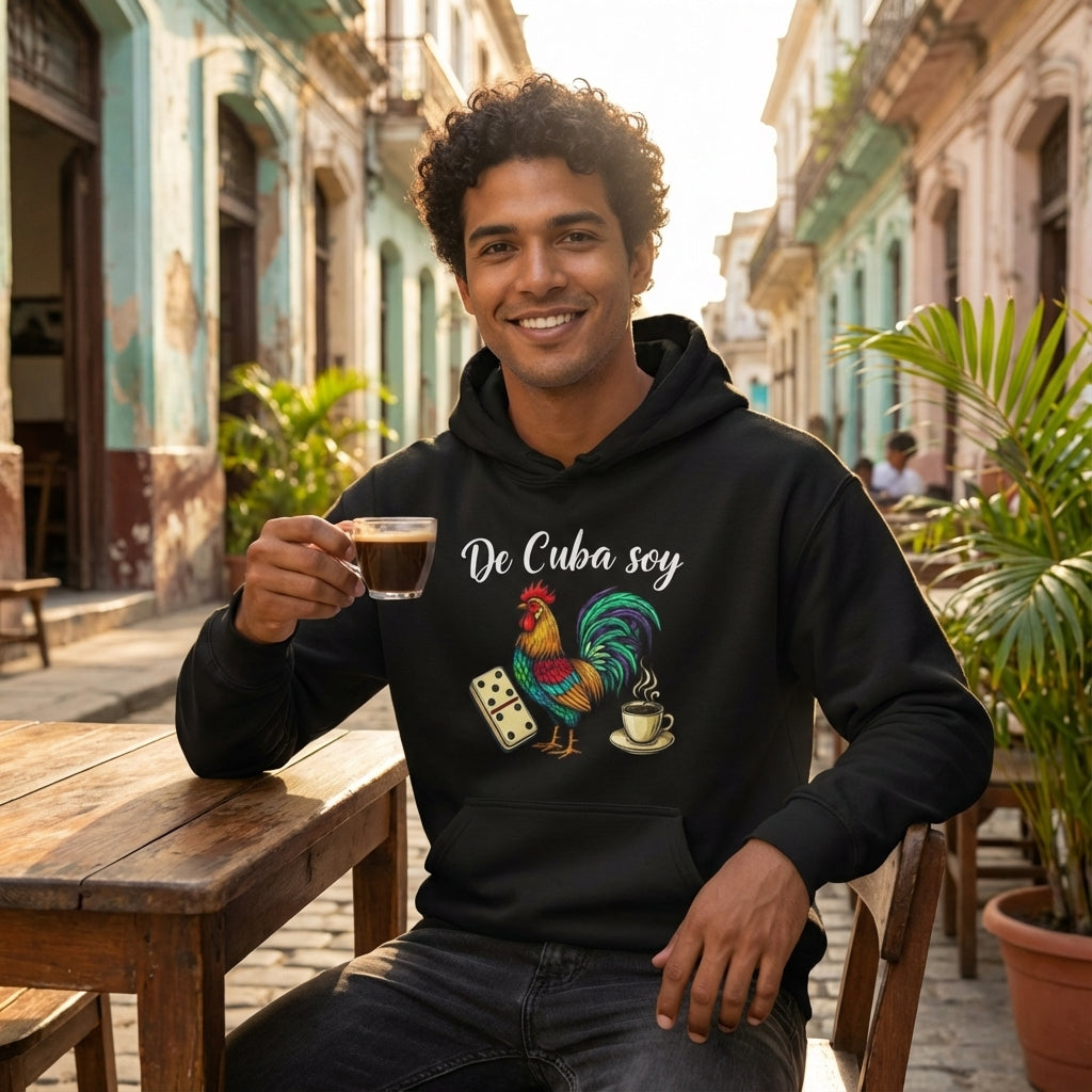 Man sitting outdoors in a tropical setting, wearing a black hoodie with a colorful rooster design and text.