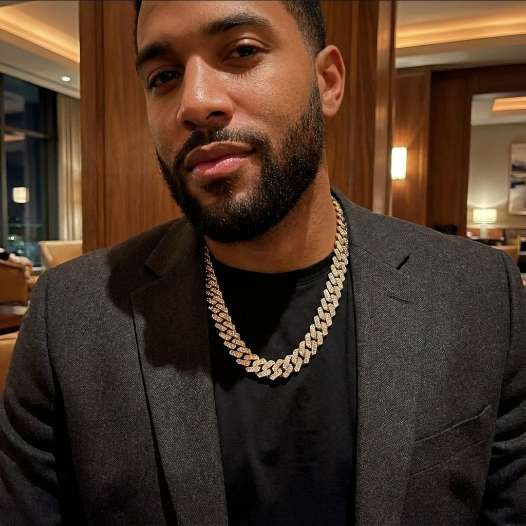 Man wearing a gray suit and gold chain necklace indoors
