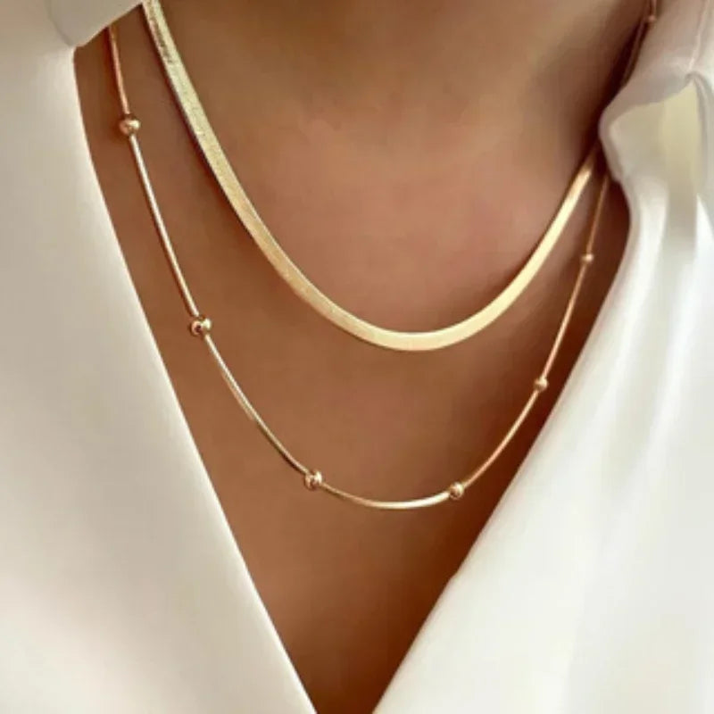 Gold necklaces on a person wearing a white top