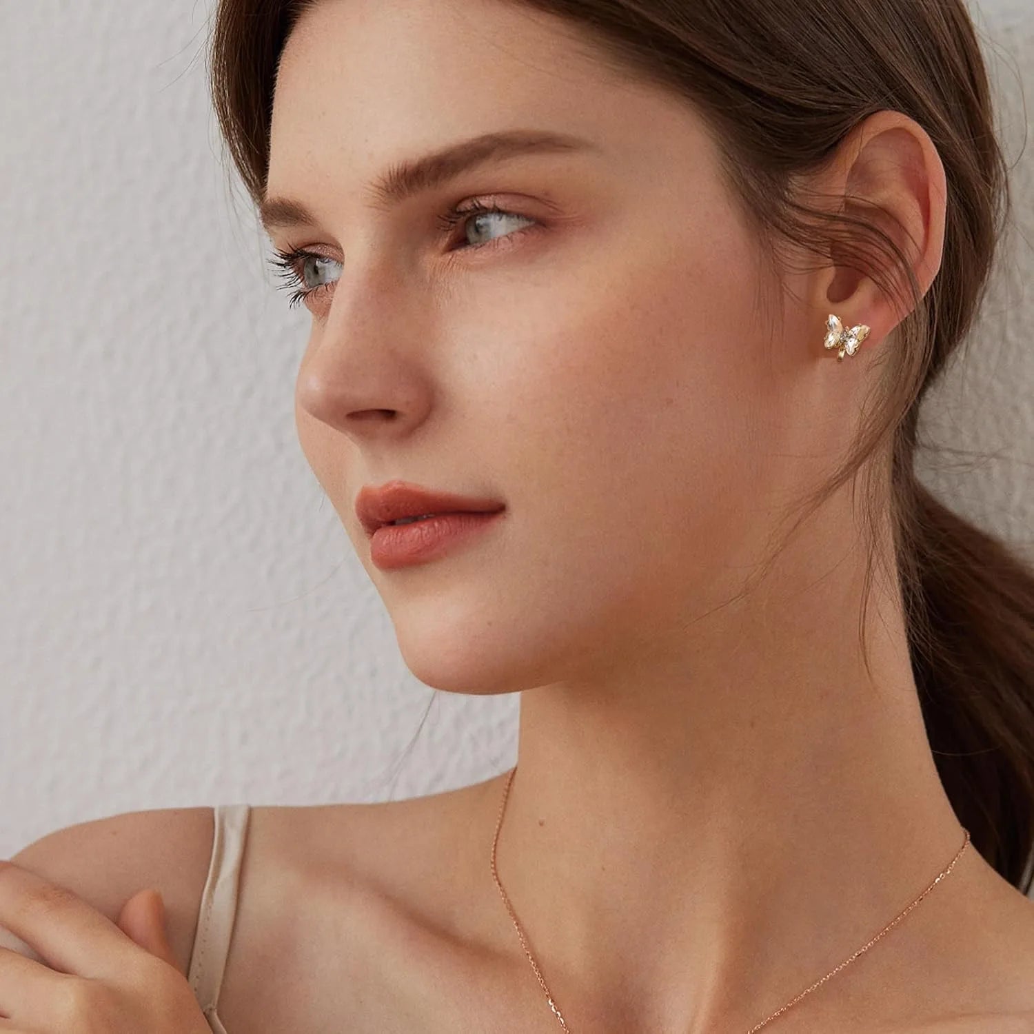 Close-up of a woman wearing a delicate earring with a neutral background