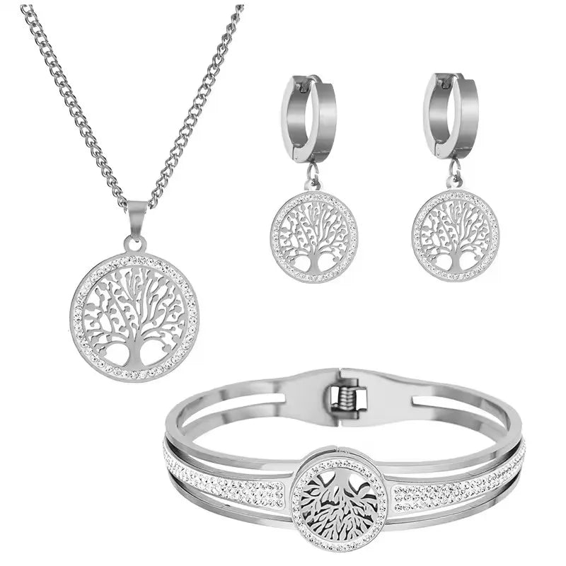 Silver jewelry set with necklace, earrings, and bracelet featuring tree-of-life design on a white background.