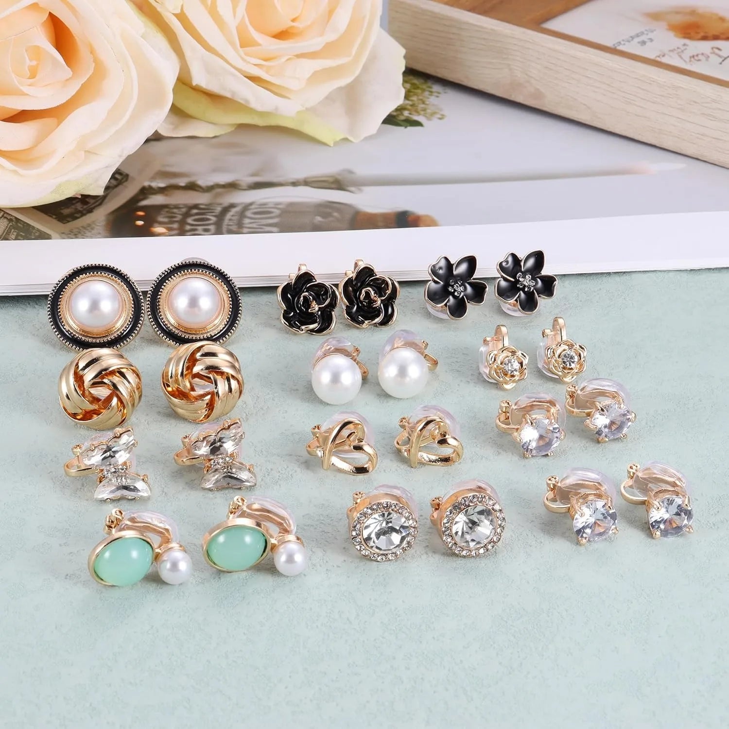 Assorted earrings on a light blue surface with flowers in the background