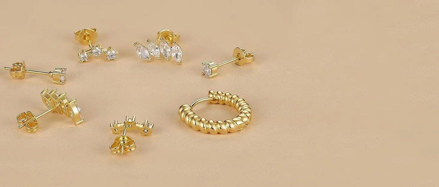 Set of gold earrings on a beige background