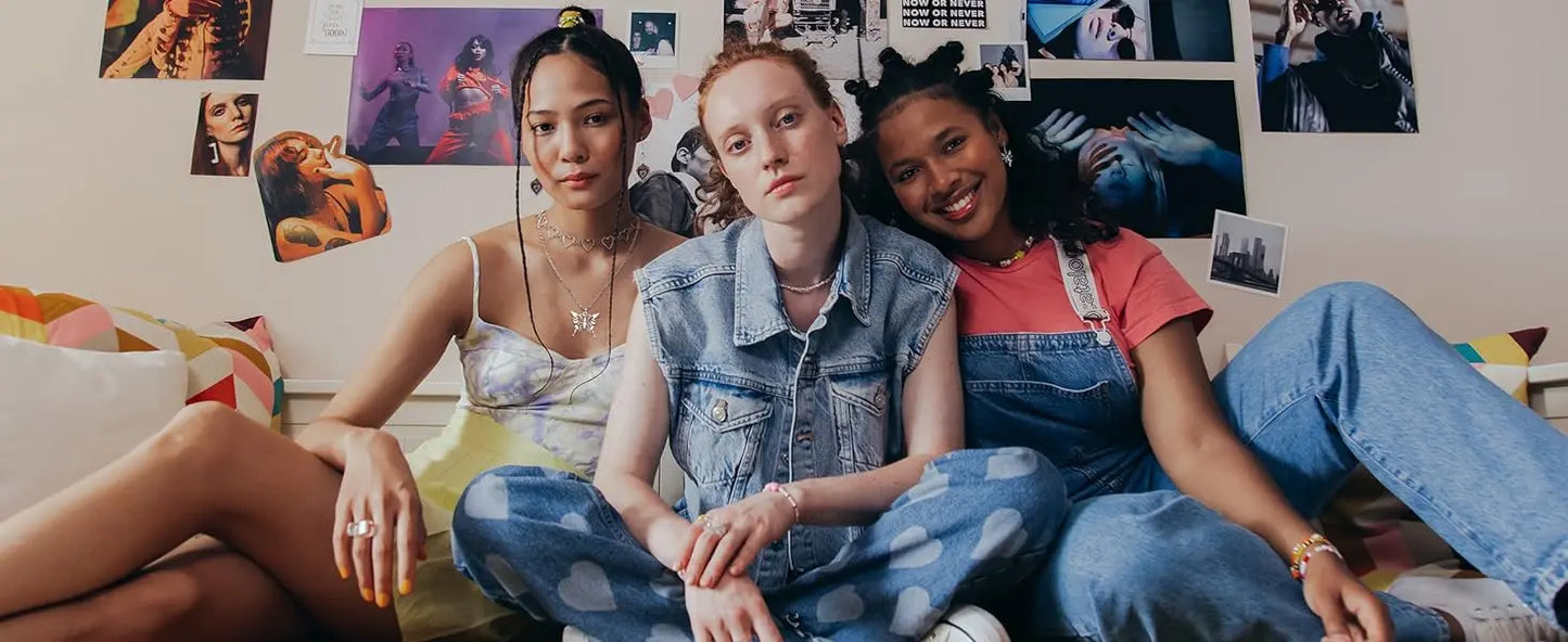 Three friends sitting together in a room with posters on the wall