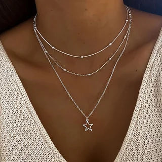 Silver star necklace on a person wearing a white top