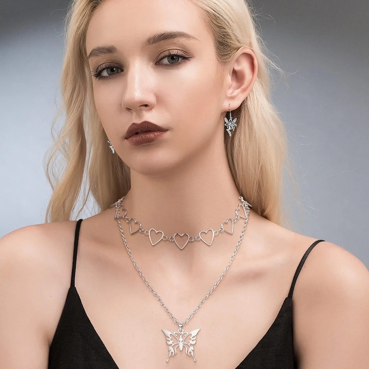 Woman wearing a butterfly necklace and earrings against a neutral background