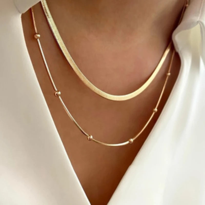 Gold necklace on a person wearing a white top