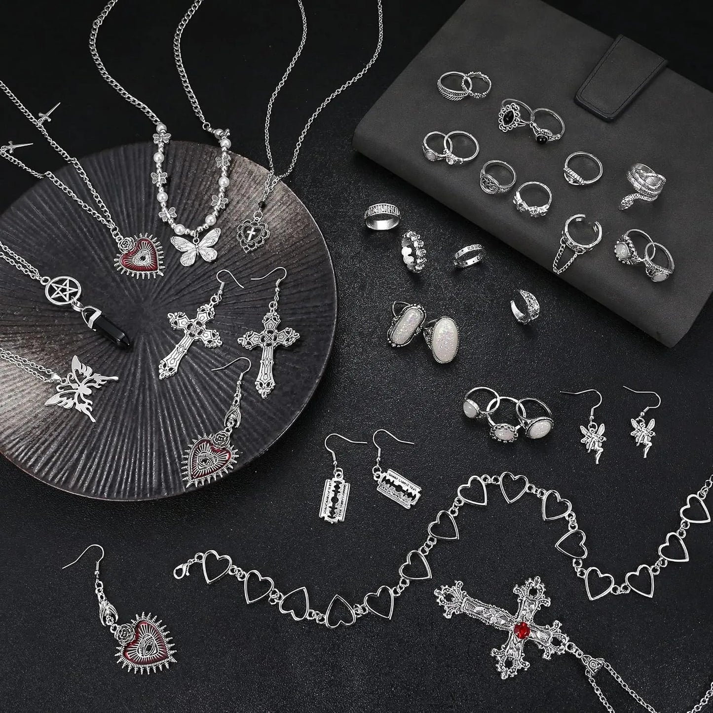 Assorted silver jewelry including necklaces, rings, and earrings on a dark surface.