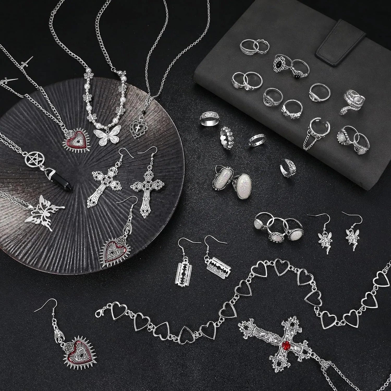 Assorted silver jewelry including necklaces, rings, and earrings on a dark surface.
