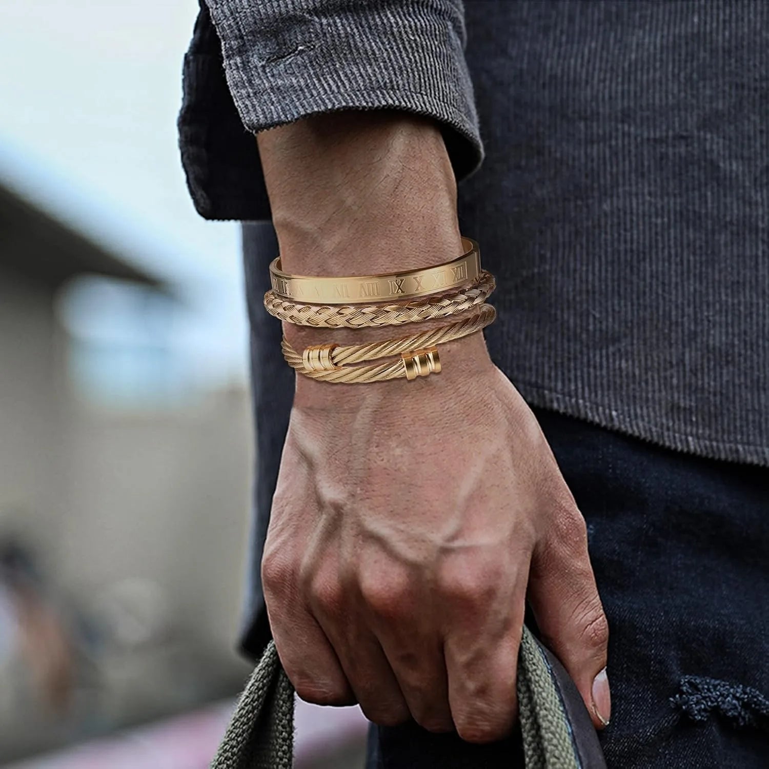 Hand wearing multiple gold bracelets with a blurred background