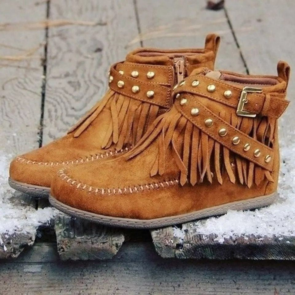 Brown suede boots with fringe and studs on a textured surface